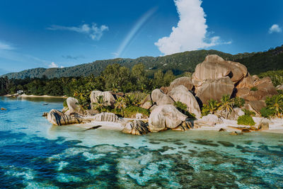 Scenic view of rocks by sea against blue sky