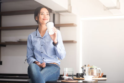 Woman having drink while sitting at home