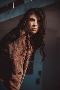 Portrait of young woman standing against wall