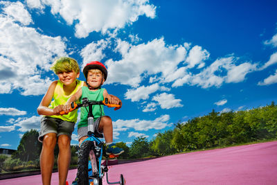 Portrait of woman riding bicycle on road against sky