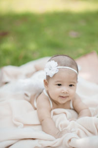 Cute baby girl wearing costume wing while lying on blanket