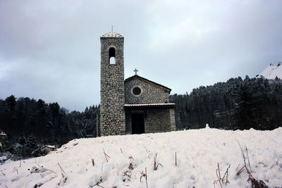 Church by building against sky during winter