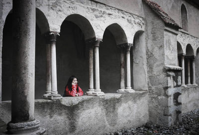 Full length of woman sitting on old building