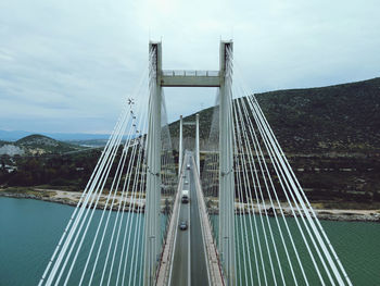 Suspension bridge over river against cloudy sky