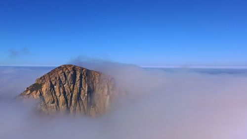 Scenic view of rock in clouds against sky