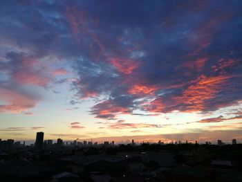 Houses in town against sky during sunset