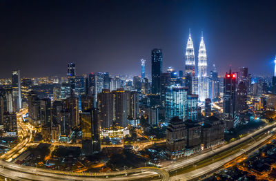 Illuminated buildings in city at night against sky