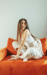 Young woman sitting on bed at home