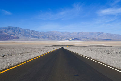 Scenic view of empty road by desert against sky
