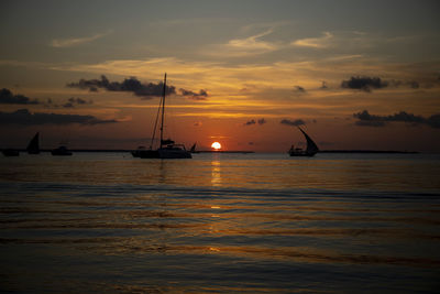 Silhouette sailboats in sea against sky during sunset