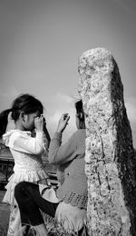 People on rock against sky