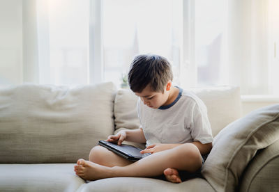 Boy looking away while sitting on sofa