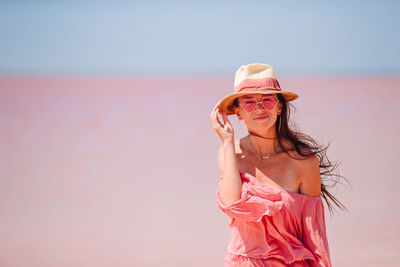 Woman with pink umbrella standing against sky