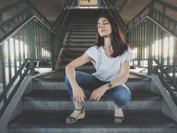 Full length of woman crouching on steps