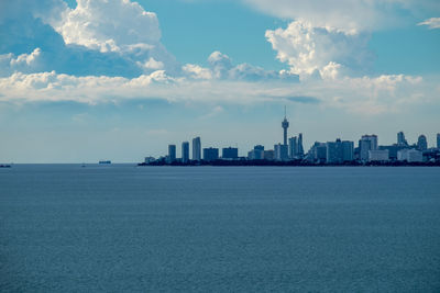 Sea and buildings in city against sky