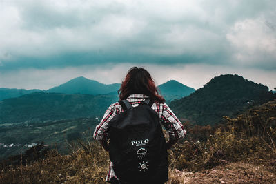 Rear view of man looking at mountains against sky