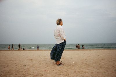 Rear view of women on beach against sky