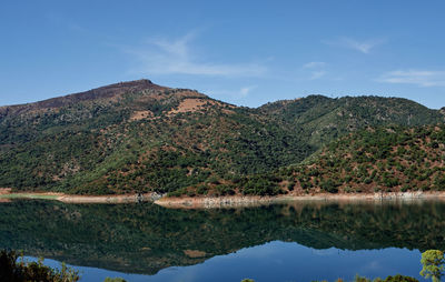 Scenic view of lake and mountains against blue sky