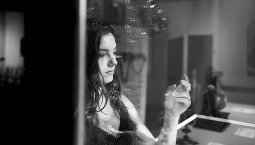 Thoughtful woman at home seen through window