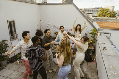 High angle view of multiracial male and female friends dancing in balcony at party