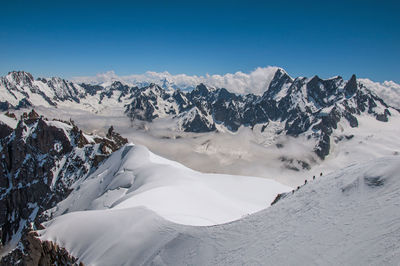 Snowy peaks and mountaineers in a sunny day at the aiguille du midi, near chamonix, france.