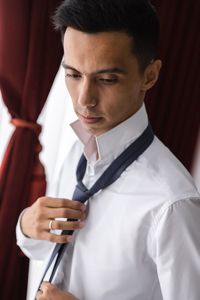 Young man holding camera while standing at home