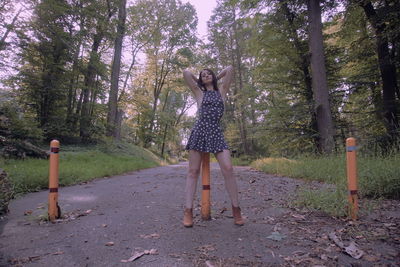 Portrait of beautiful fashion model standing on road against trees