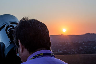 Rear view of man against orange sky