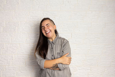 Smiling young woman standing against wall