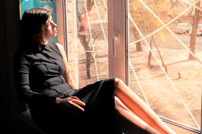 Woman looking through window at home