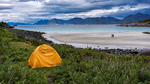 Yellow tent near empty beach with fjords over the horizon