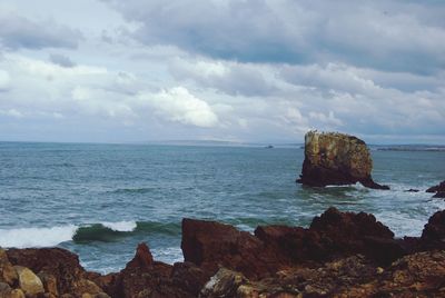 Rocks on sea shore against sky