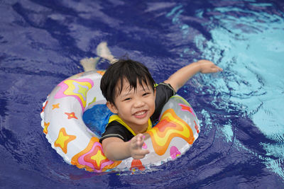 High angle portrait of cute boy with inflatable ring in swimming pool