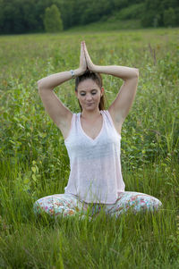 Young woman practicing yoga while sitting on grassy field