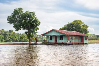 House by lake against sky