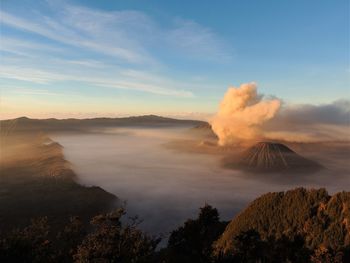 Smoke emitting from volcanic mountain against sky during sunset