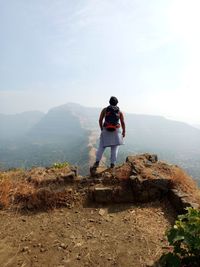 Rear view of man standing on mountain against sky