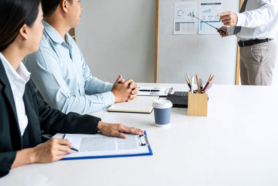 Midsection of businessman giving presentation to colleagues in office