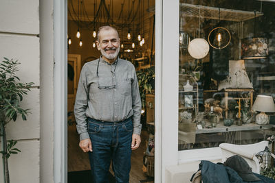 Happy male entrepreneur standing at entrance of home interior shop