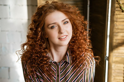 Portrait of happy redhead young woman near window