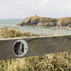 Information sign on beach against sky