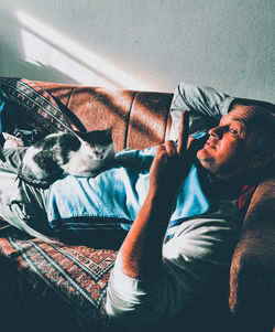 Man with cat lying on sofa at home