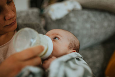 Close-up of mother feeding baby boy while sitting at home