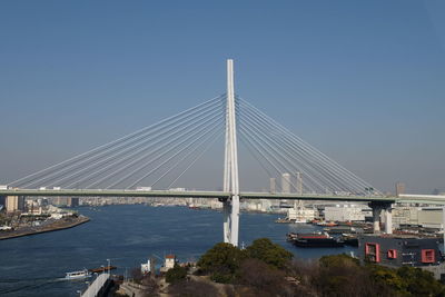 Suspension bridge over river against clear blue sky