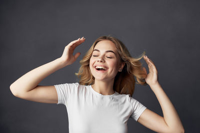 Portrait of smiling young woman against black background