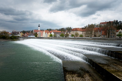 River by cityscape against sky