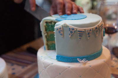 Cropped hand of person cutting cake from knife