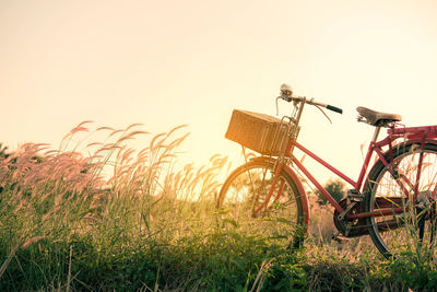 Bicycle on field against sky during sunset