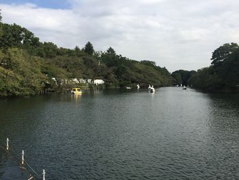 Boats on lake by trees against sky