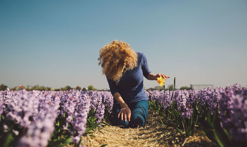 Woman with flowers on field against clear sky